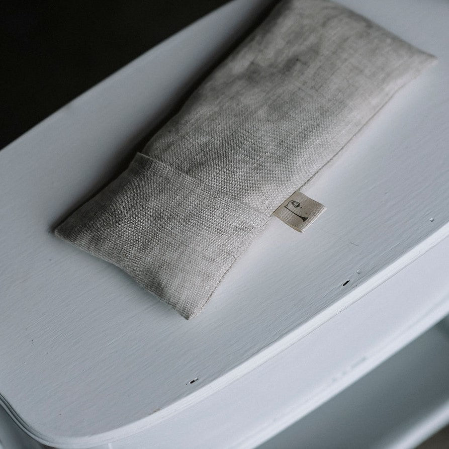 Petit coussin apaisant de couleur naturelles sur meuble blanc vu d'en haut.