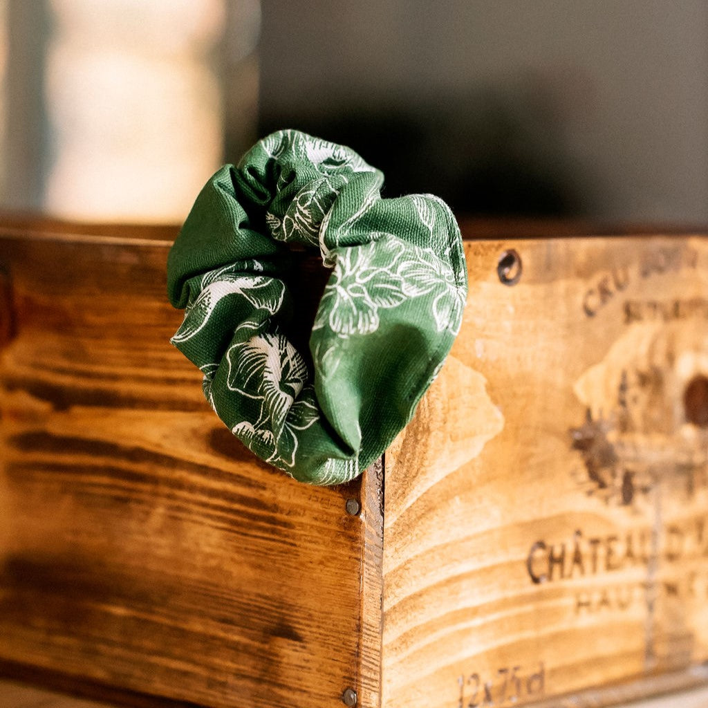 Chouchou à cheveux coulleur vert olive avec fleurs blanches  sur boîte en bois.