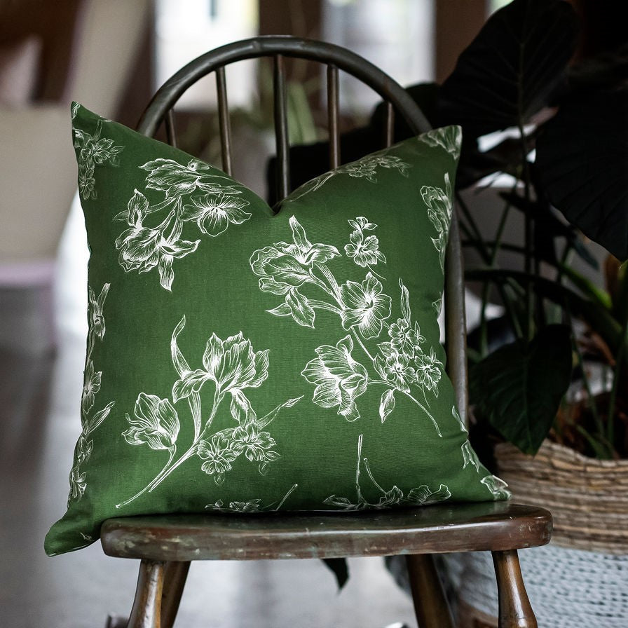 Coussin vert avec fleur blanche sur chaise en bois