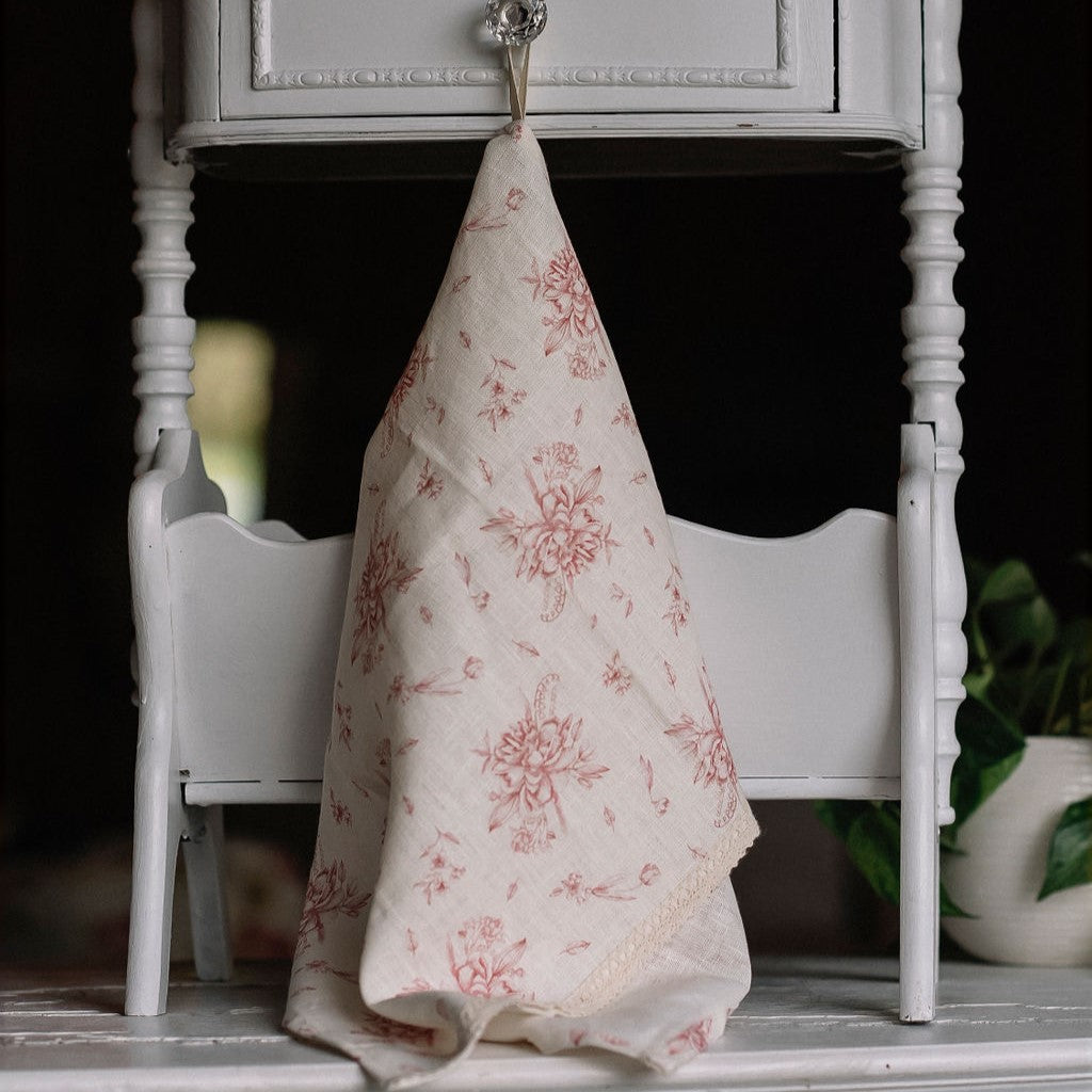Linge à vaisselle fleurs des champs roses avec dentelle suspendu au meuble en bois blanc.