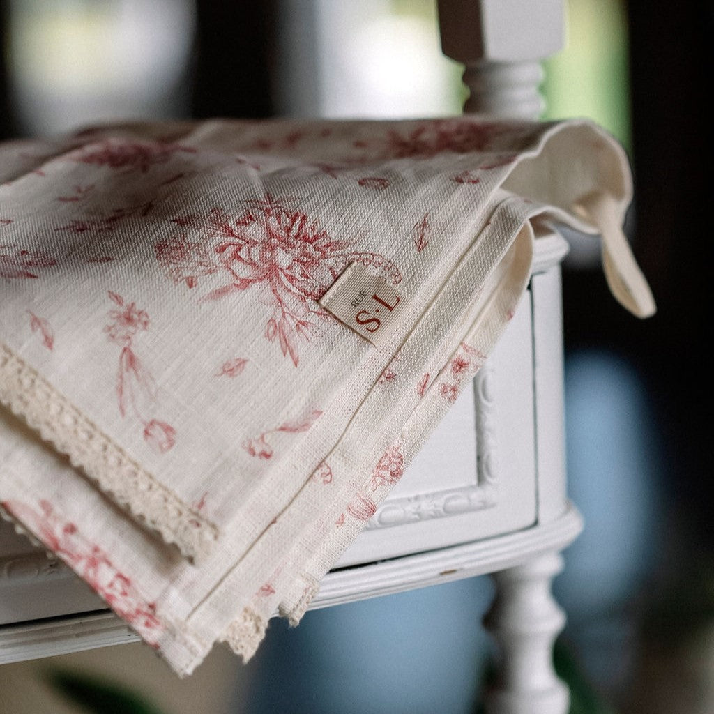 Linge à vaisselle fleurs des champs roses avec dentelle sur meuble en bois blanc.