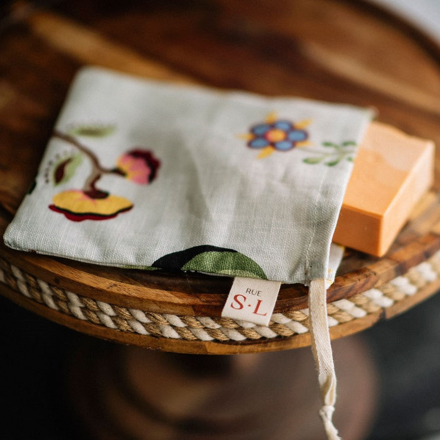 Pochette à savon fleurs colorées sur présentoir en bois avec savon orange à l'intérieur