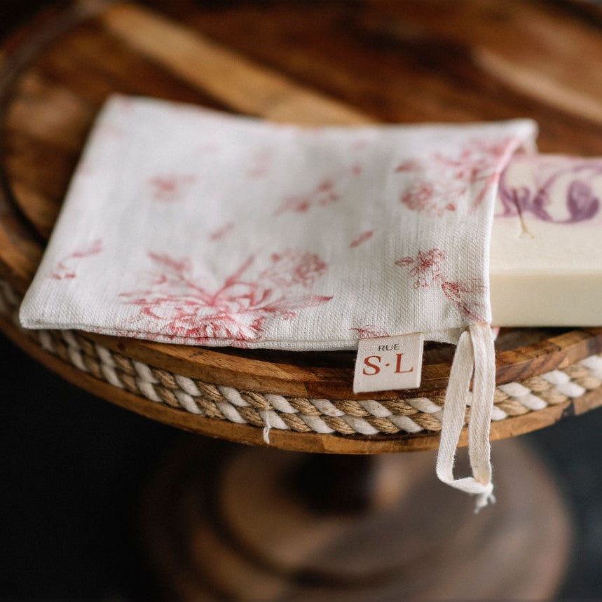 Pochette fleurs rose sur présentoir en bois avec savon blanc et mauve