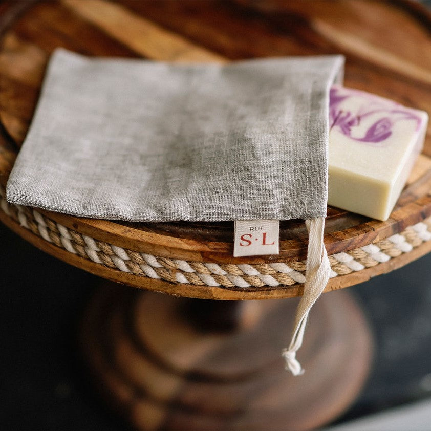 Pochette lin naturelle sur présentoir en bois avec savon blanc et mauve