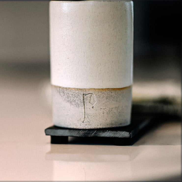 Bas de pompe à main en céramique avec logo SL sur planche d'ardoise.