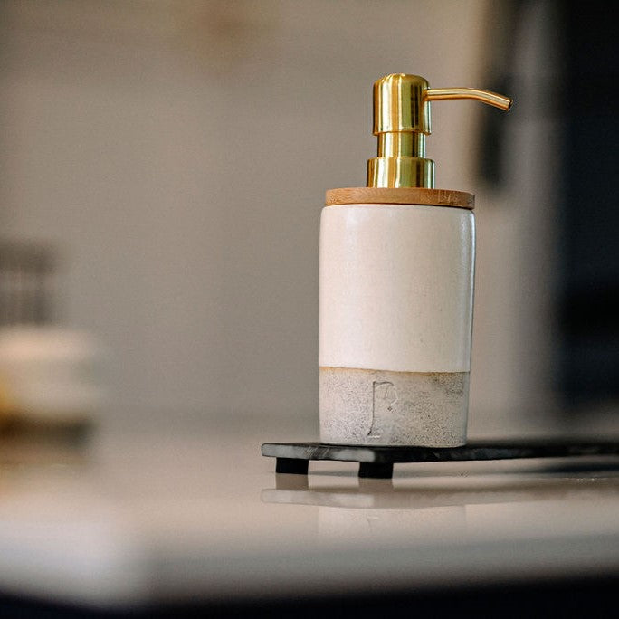 Pompe à savon en céramique de couleur or sur planche d'ardoise.