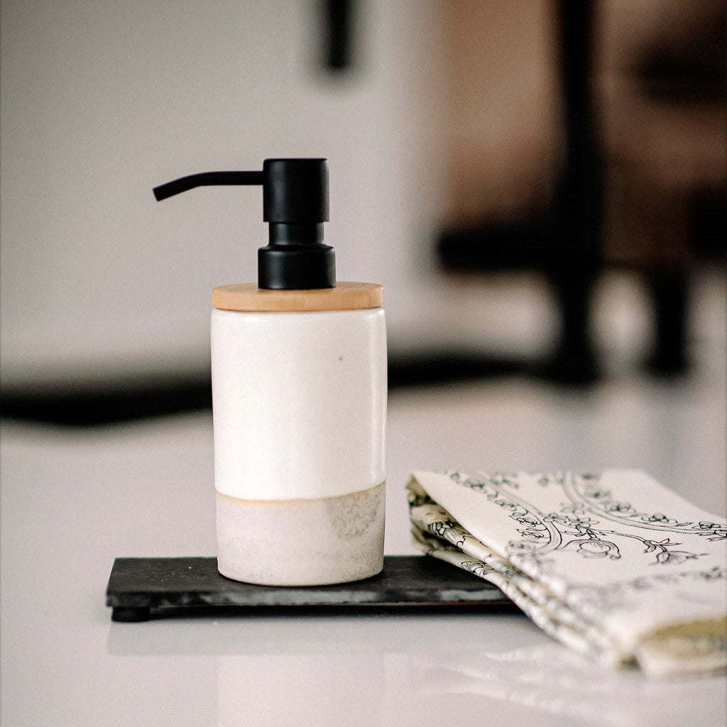 Pompe à savon en céramique de couleur noire sur planche d'ardoise noire avec linge à main
