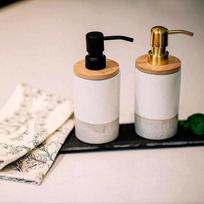 Pompes à savon en céramique  de couleurs noire et or sur planche d'ardoise et linge à main.