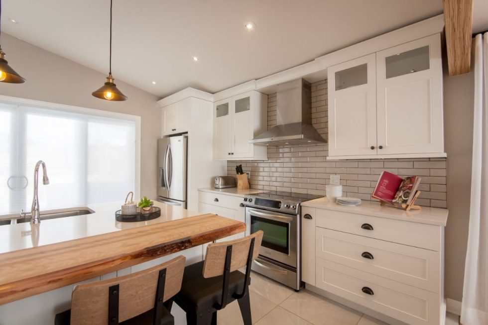 une cuisine avec des armoires blanches et un îlot en bois.