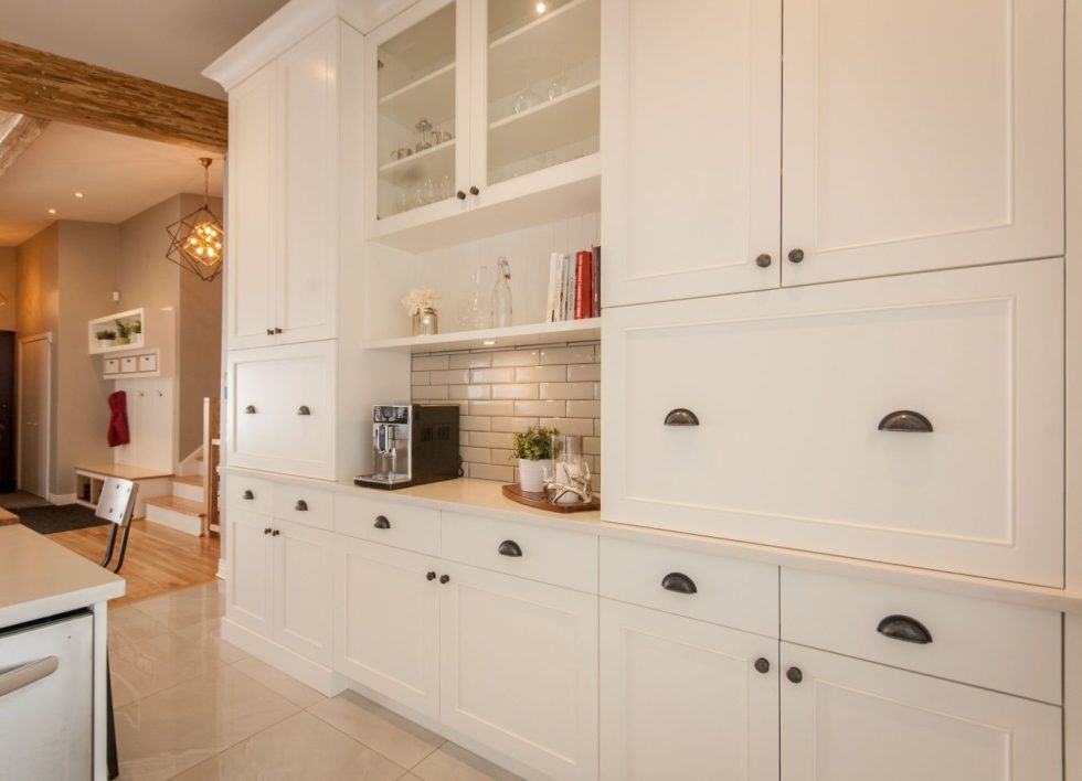 une cuisine avec armoires et étagères blanches.