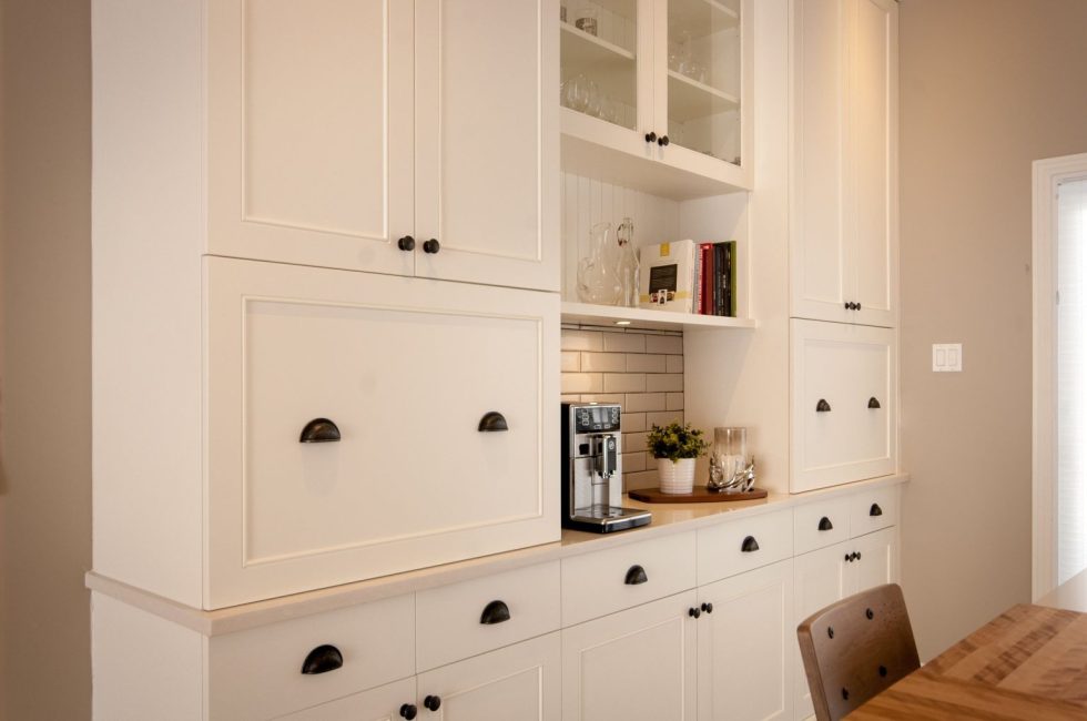une cuisine avec des armoires blanches et des poignées noires.