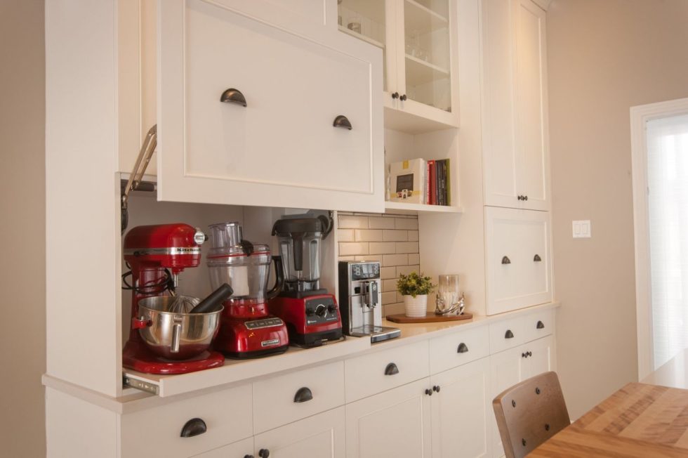 une cuisine avec des armoires blanches et des mélangeurs rouges.