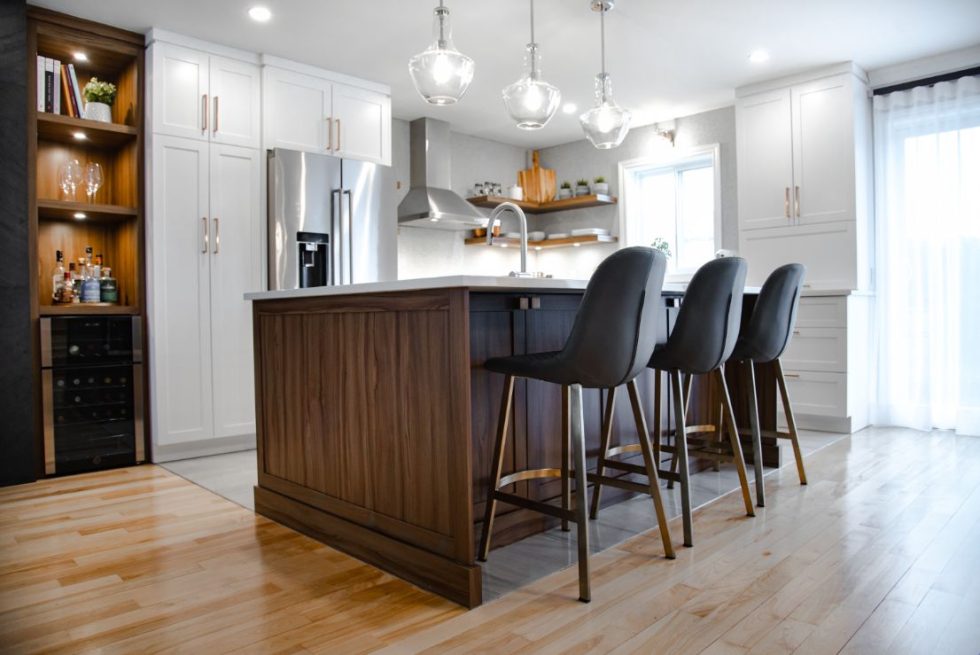 une cuisine avec un îlot central entouré de tabourets de bar.