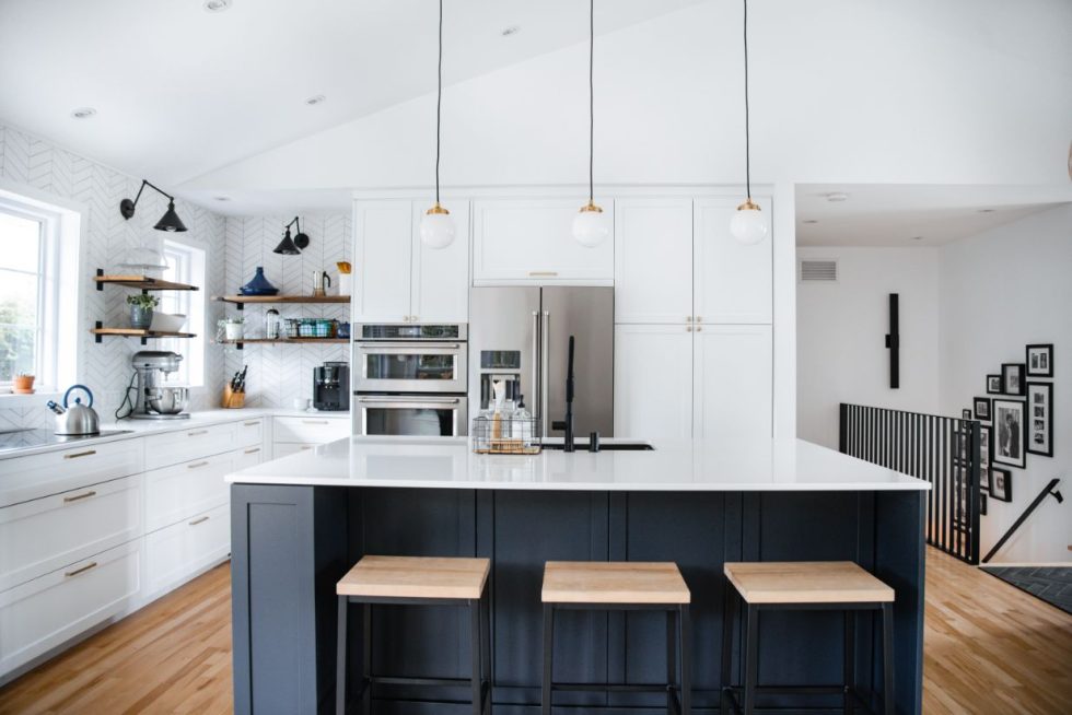 une cuisine avec des armoires blanches et un îlot noir.