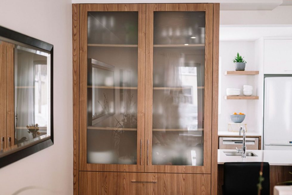 une armoire en bois avec des portes vitrées dans une cuisine.