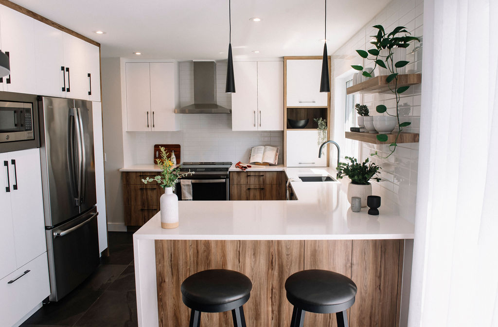 Salle de bain moderne avec meuble-lavabo en bois, lavabo blanc, miroir rond, porte-serviettes, cadre floral, murs verts et carrelage hexagonal noir et blanc. Une petite fenêtre se trouve au-dessus du porte-serviettes.