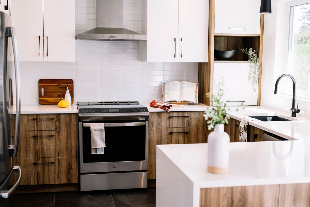 Salon et salle à manger modernes avec de grandes fenêtres, des canapés marron, une cheminée noire, une télévision à écran plat, une table à manger en verre avec des chaises beiges et une vue sur un lac à travers les fenêtres.